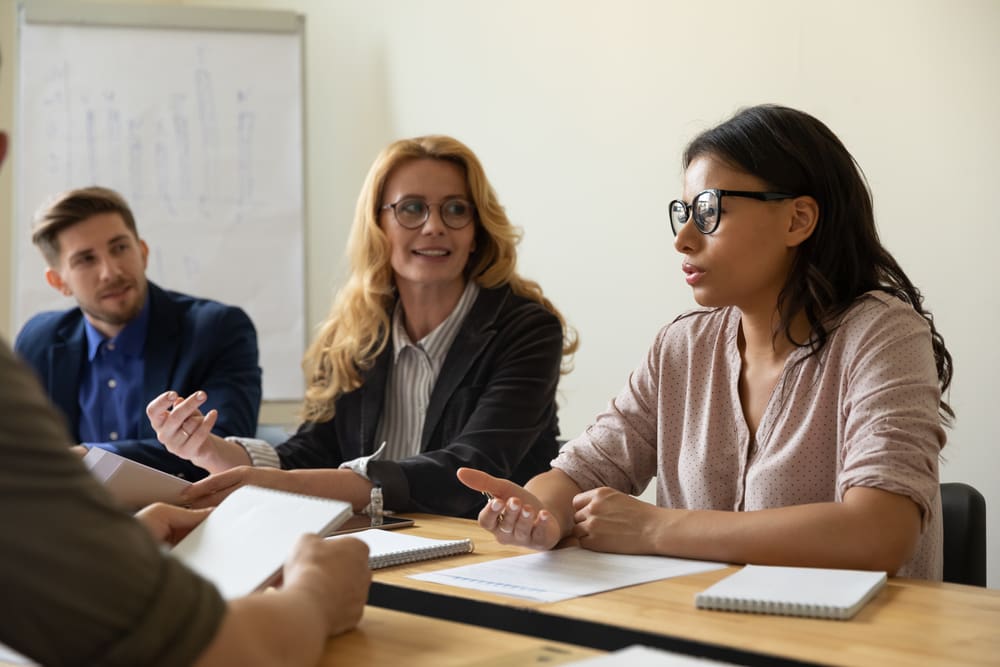 Professional meeting of co-workers and interns in a boardroom.